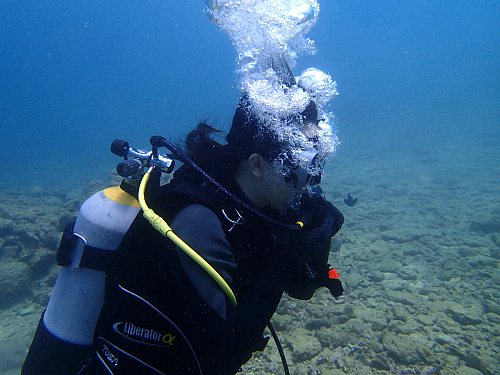 海洋実習で、講習生がレギュレーターリカバリーの練習で、レギュレーターの中の水を吐き出している写真